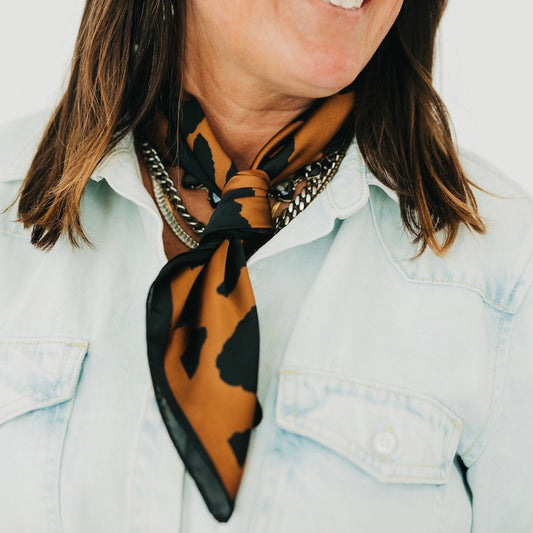 Leopard square scarf with black and brown spots, tied at the neck