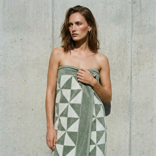 Sage and ecru geometric cotton towel with triangle pattern, draped over a person’s shoulder.