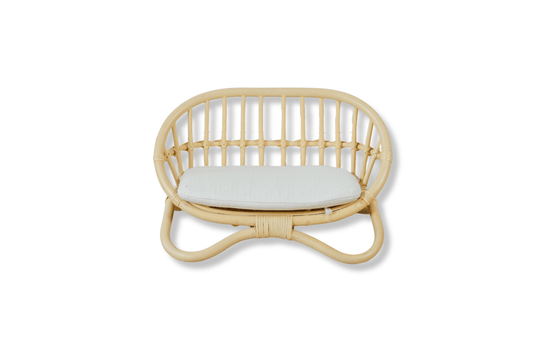 Natural rattan miniature doll couch with curved slatted back and white seat cushion