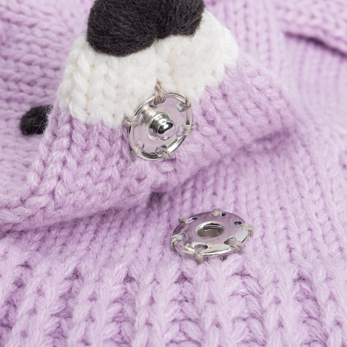 Close-up of the knit fox scarf's snap fastener beside its white muzzle
