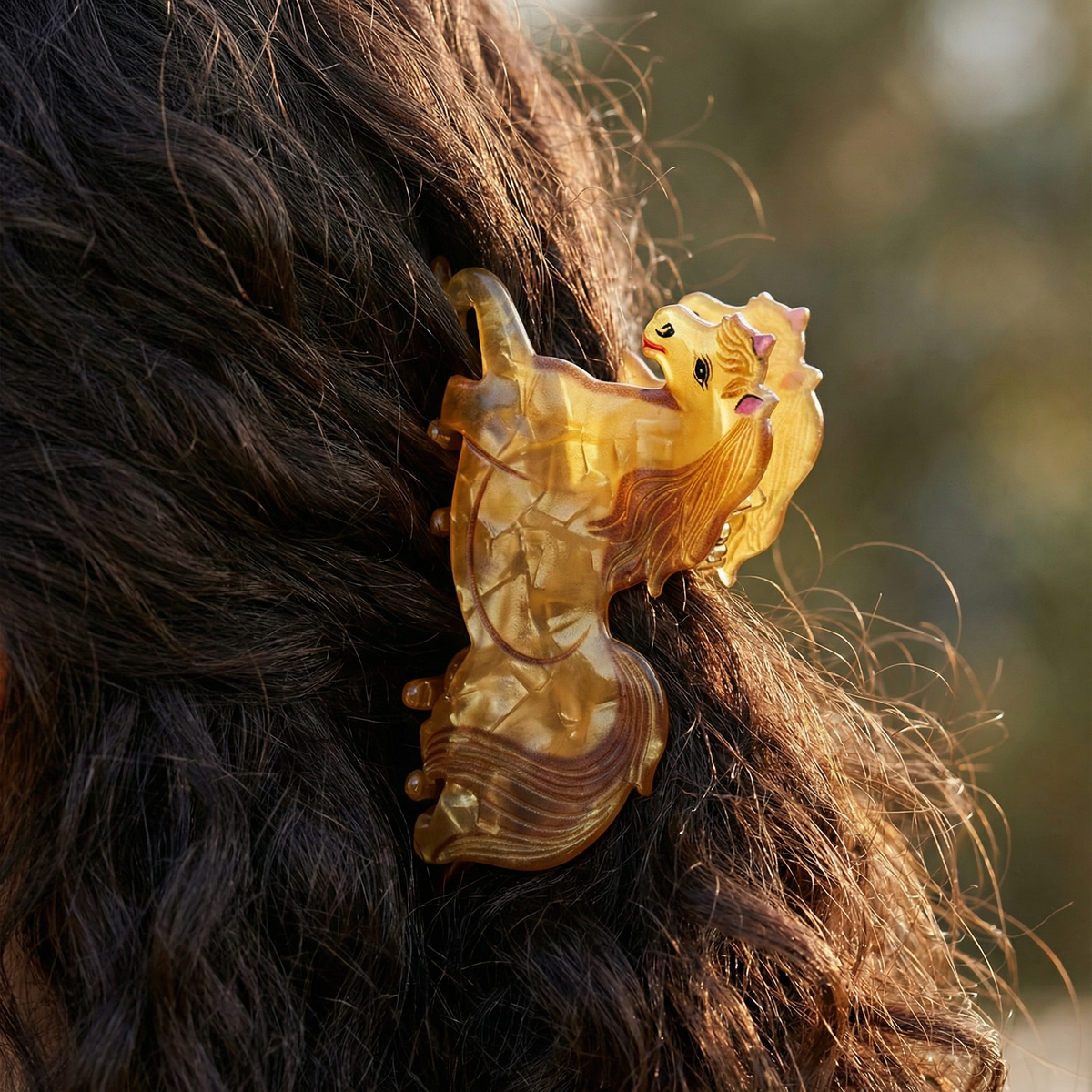 Gold horse-motif hair claw clipped on dark brown hair
