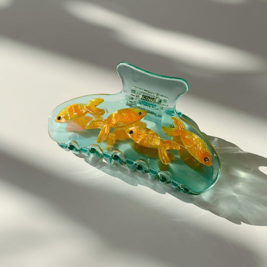 Goldfish hair claw clip, angled view of teal transparent base with golden fish