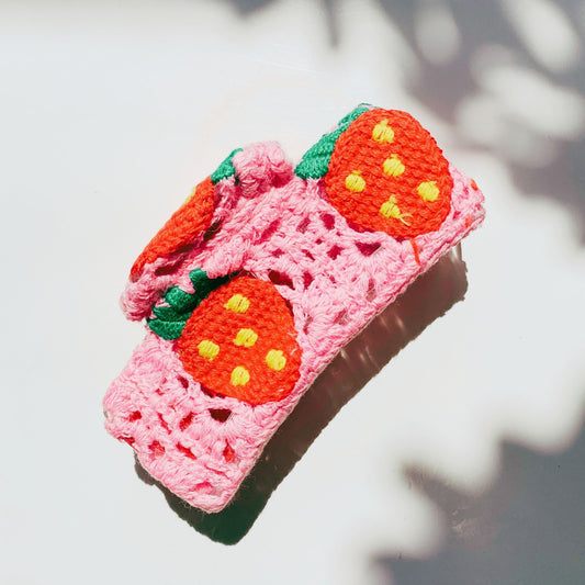 Pink crocheted hair claw with orange strawberry faces and green leaf accents