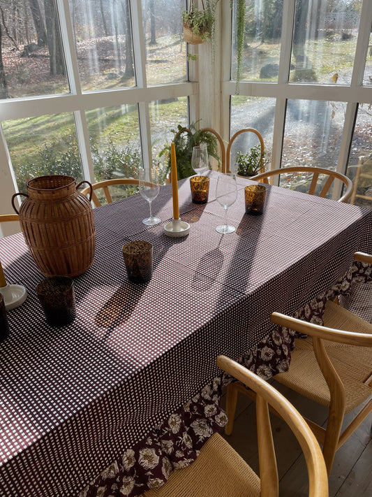 Wine gingham tablecloth with a floral ruffle around the edge, shown covering a dining table