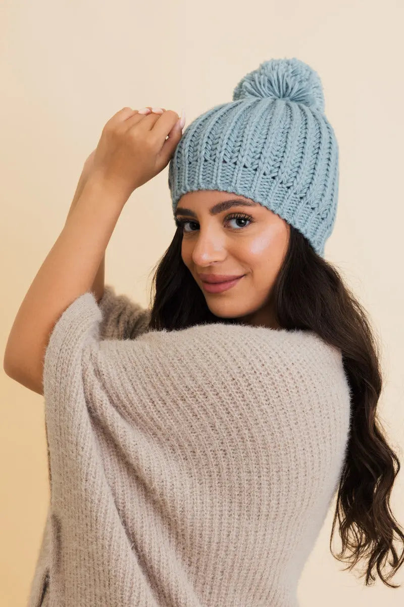 Sea blue cable-knit pom beanie with folded cuff and pom on top, front view.