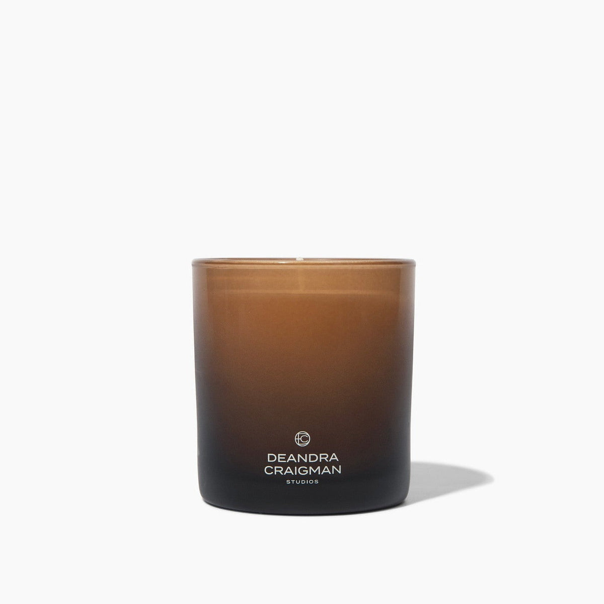 Brown scented candle in frosted glass jar with Deandra Crayons label