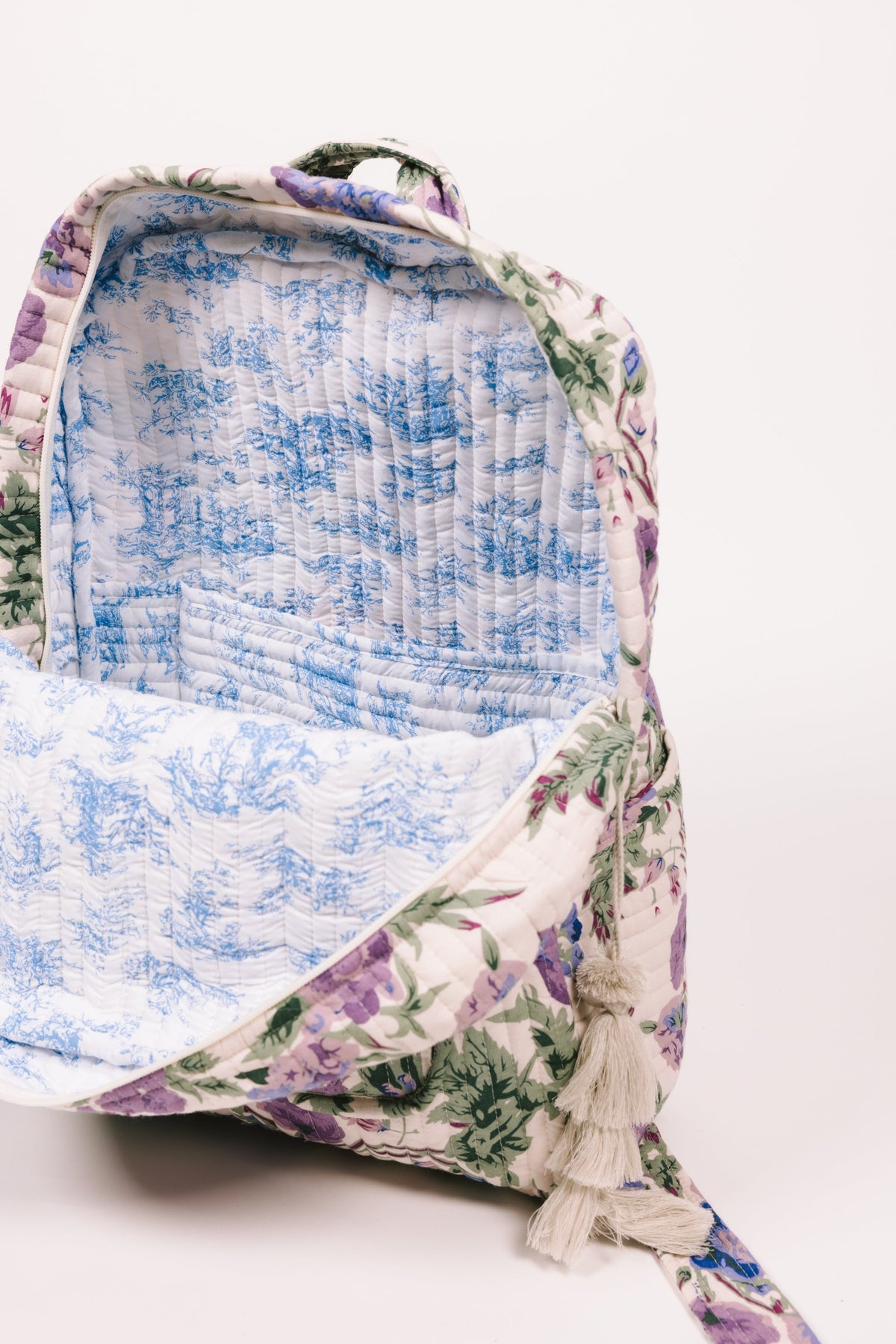 Quilted floral backpack interior view with blue fabric lining and tassel edge
