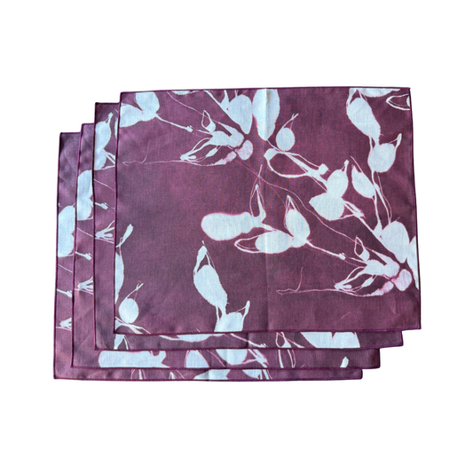 Stack of rectangular aubergine placemats with light blue floral print and stitched edges.