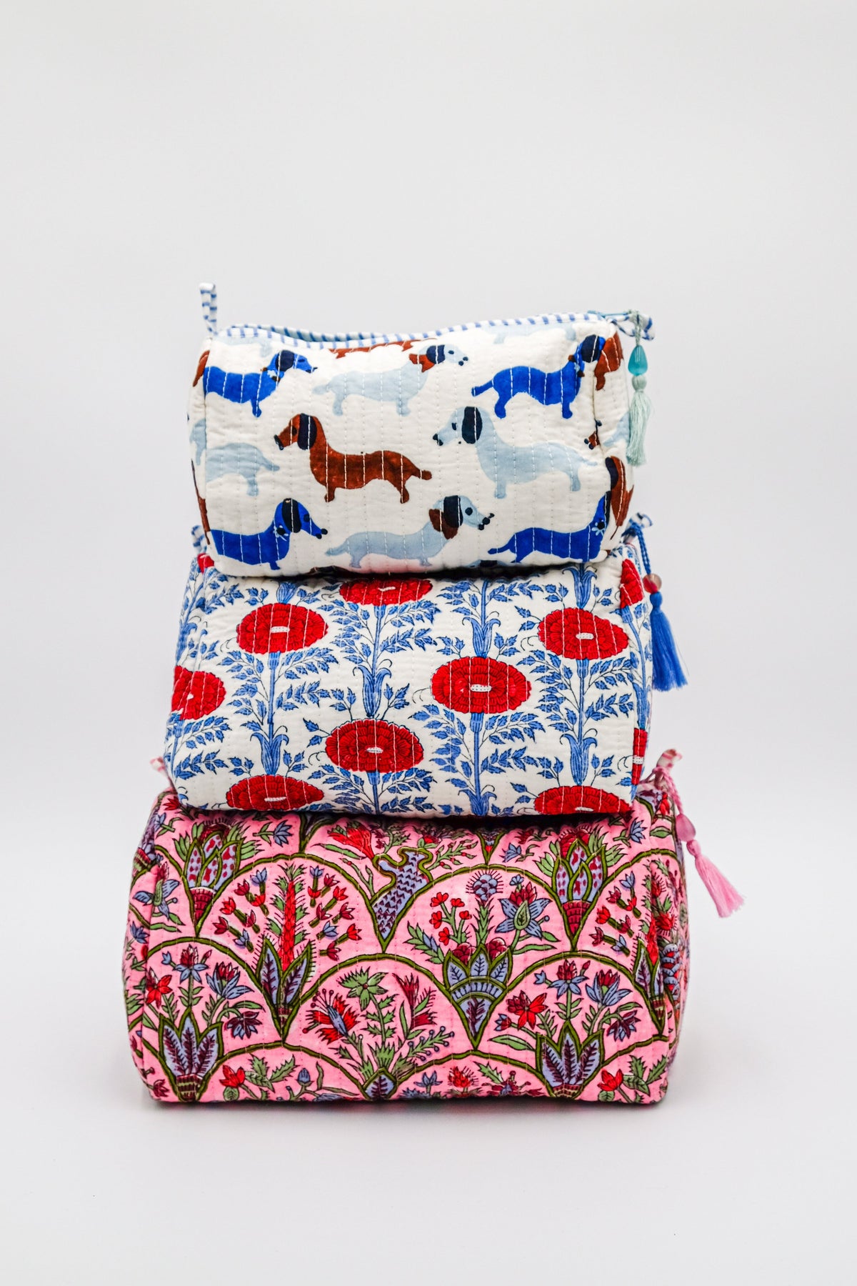 Toiletry bag with blue cow print panel, pink floral base, and tassel ties