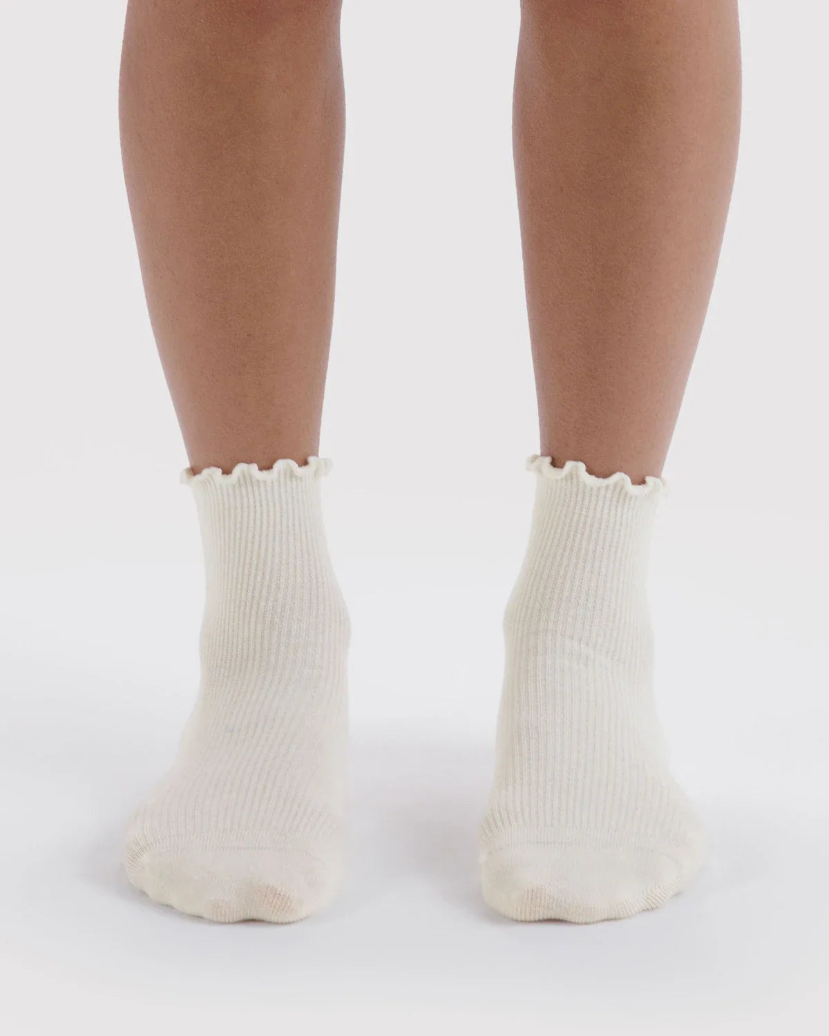 White ribbed lettuce-edge socks worn on feet
