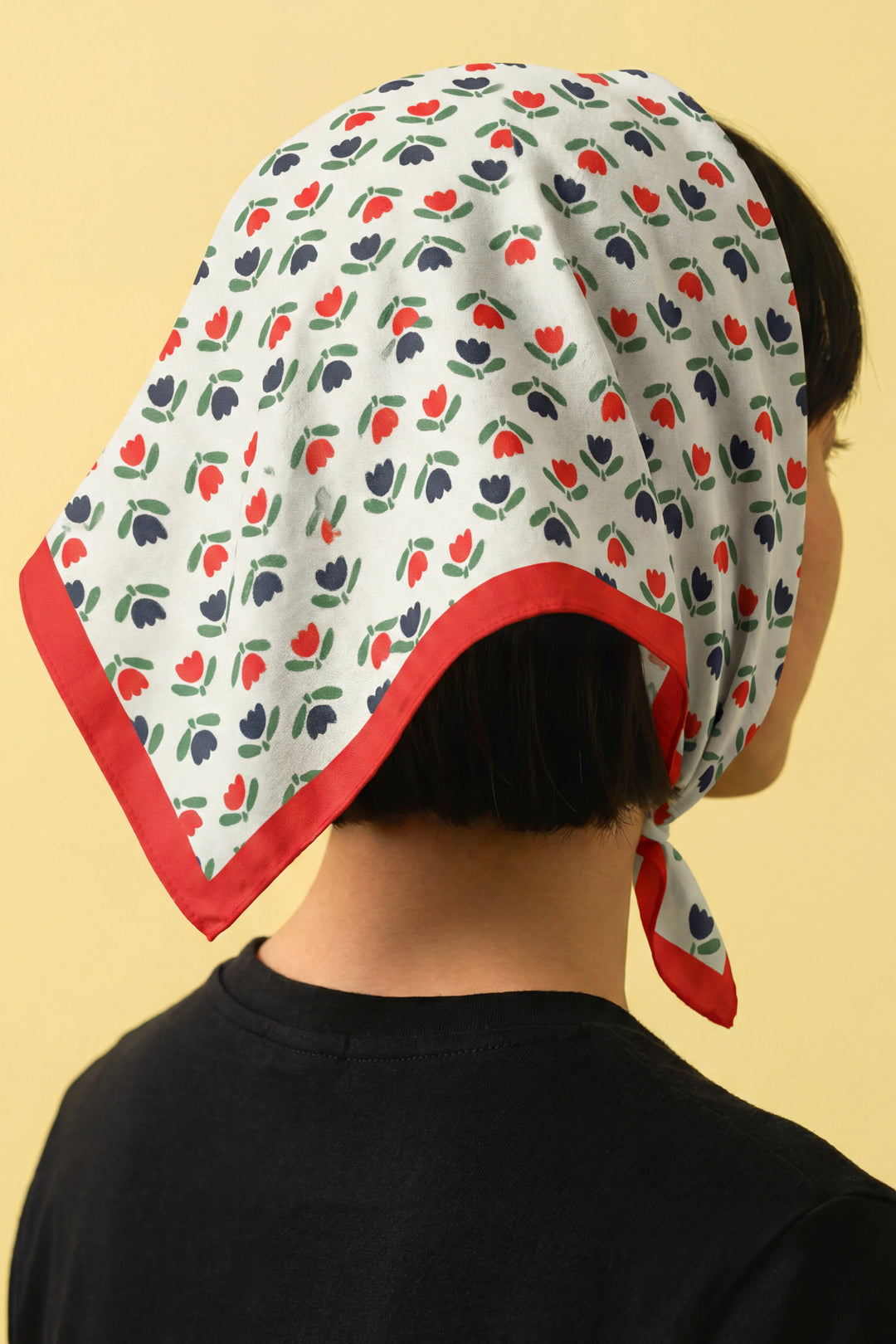 Cotton headscarf bandana on wearer, white tulip print with red border, side view