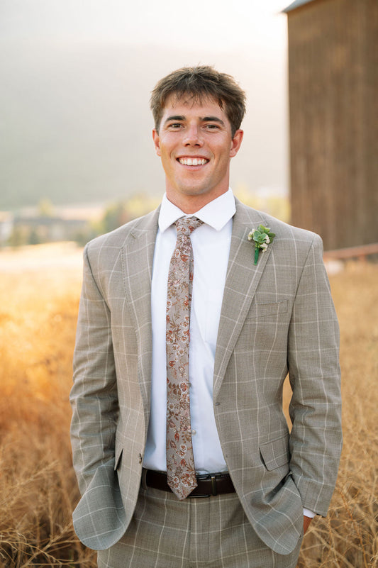 Men's floral necktie in beige with rust and gold tones, worn with white shirt