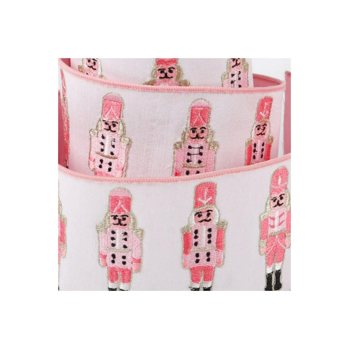 Close-up nutcracker dupion ribbon: white fabric, pink trim, repeating nutcracker soldiers