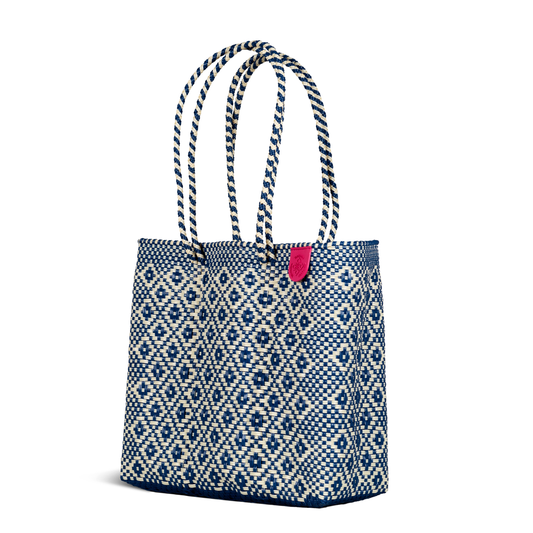 Woven tote bag with blue diamond geometric pattern and pink fabric tag on front