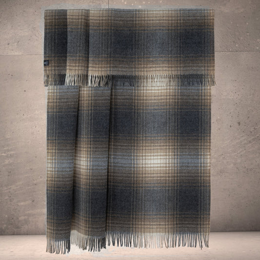 Natural-toned ombre plaid lambswool throw blanket with long fringes, hanging fold.