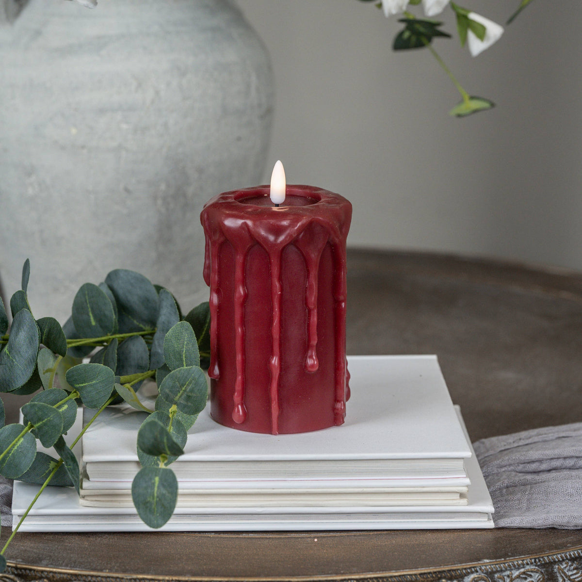 Red 3D flame pillar candle with raised drip pattern and lit wick