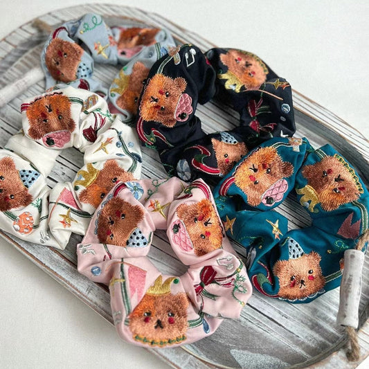 Assorted bear scrunchies with embroidered faces on white, black, pink, and teal bases