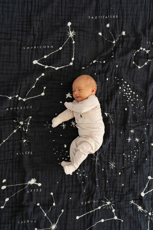 Black astrology blanket close-up with scattered constellation lines and moon graphic