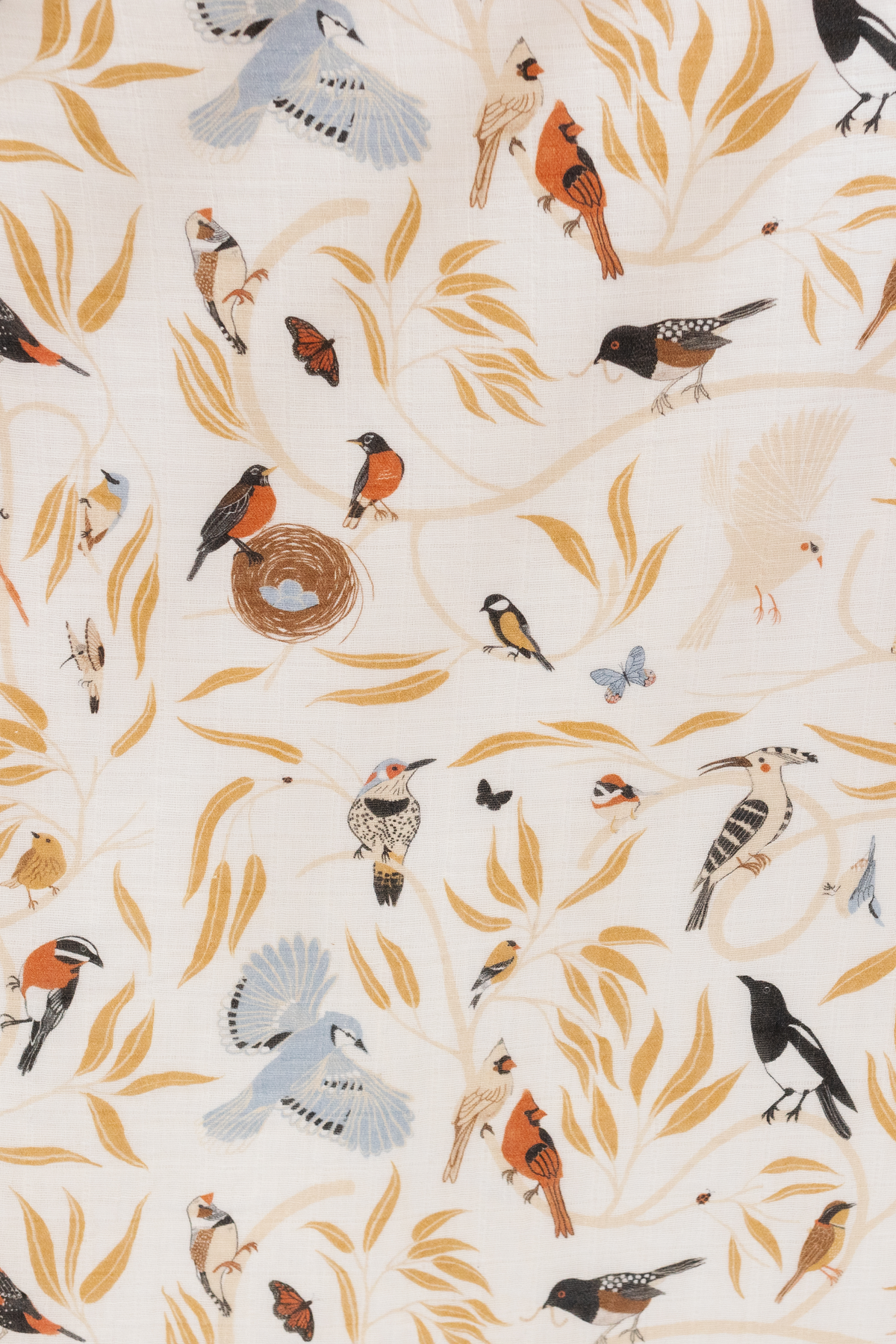 Close-up of white crib sheet fabric with scattered birds, butterflies, and leaves print