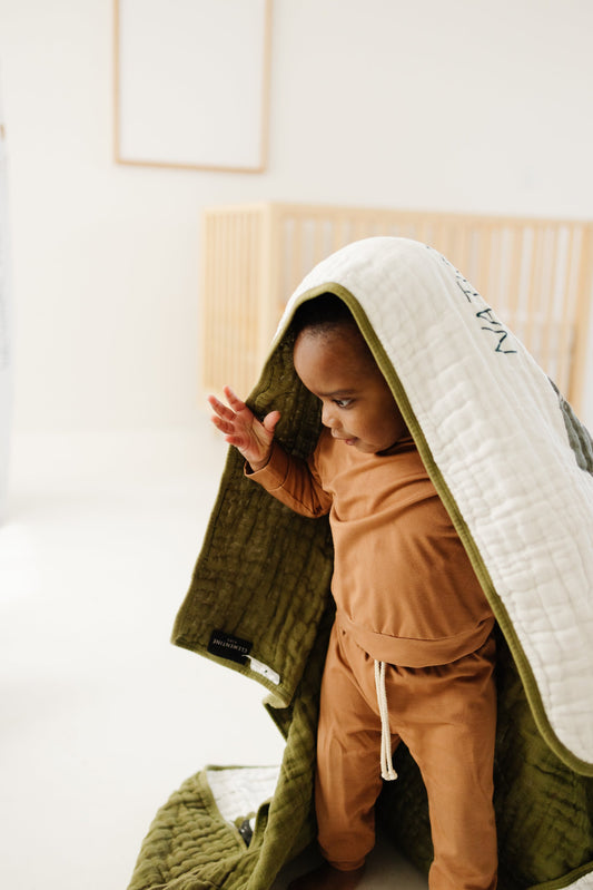 White quilted blanket with national park print, draped as a hood over a child.