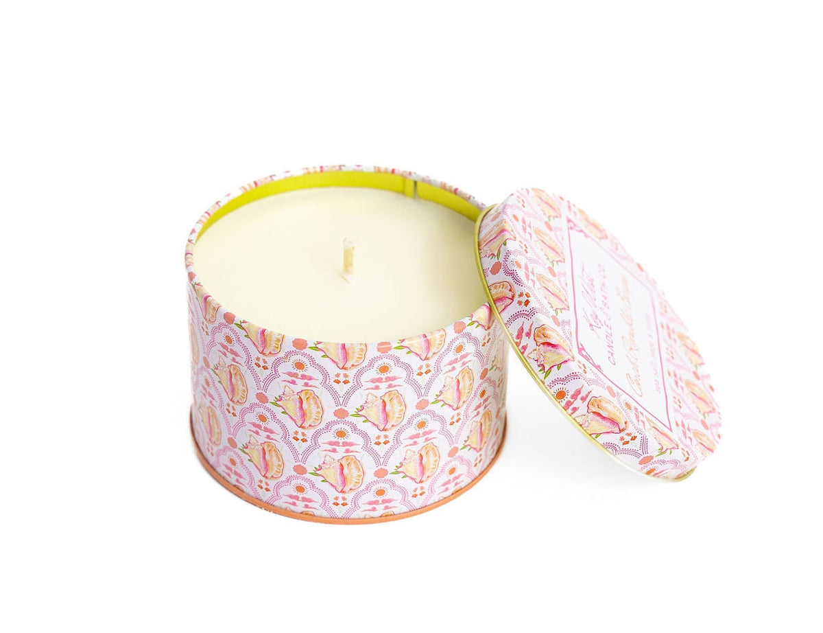 Pink patterned travel tin candle with lid open, cream wax visible inside