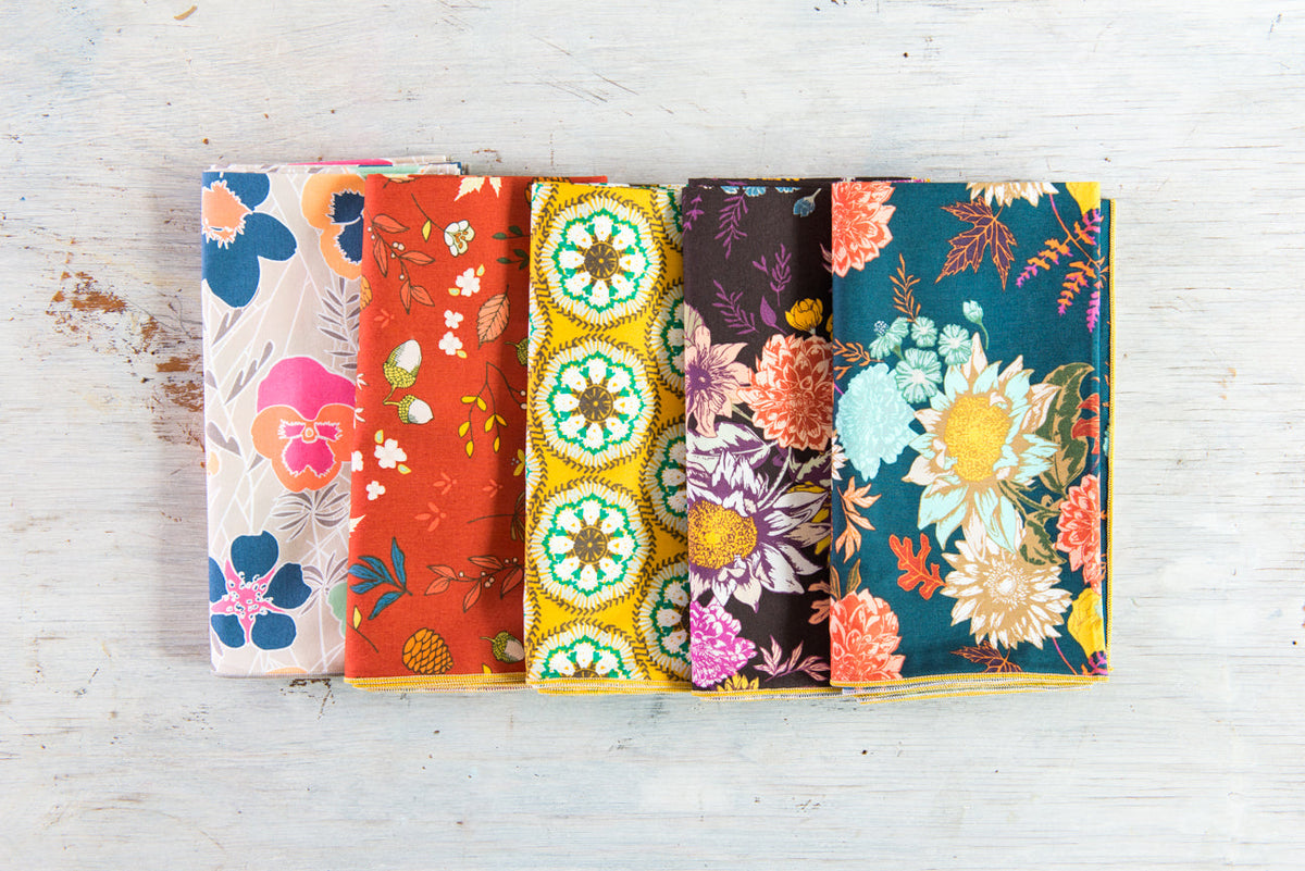 Bundle of four floral cloth napkins with coordinating navy, teal, orange, and gold medallions