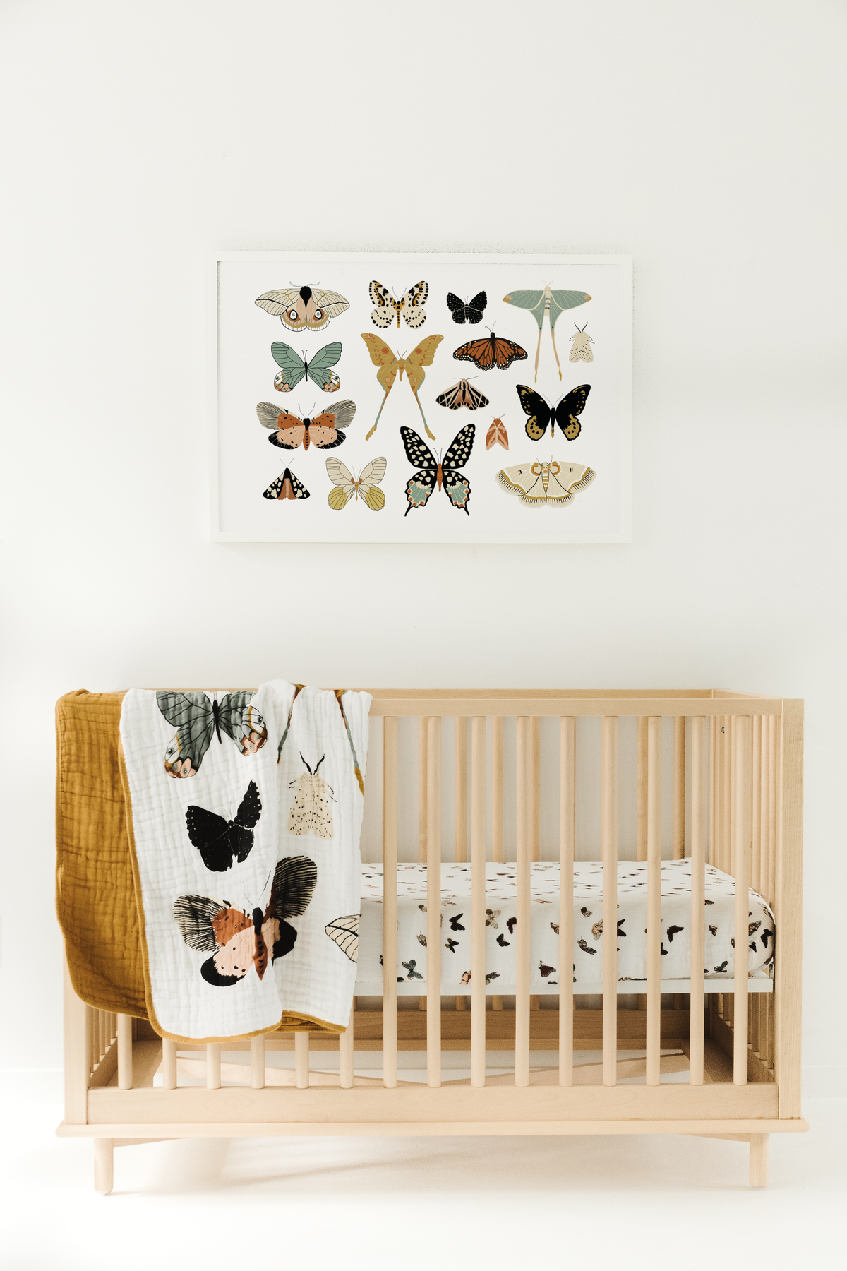 Butterfly collector quilt on a wooden crib, white and mustard with multicolor butterflies