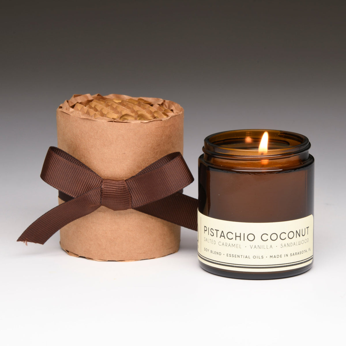 Amber glass candle jar with white label and kraft gift wrap with ribbon bow