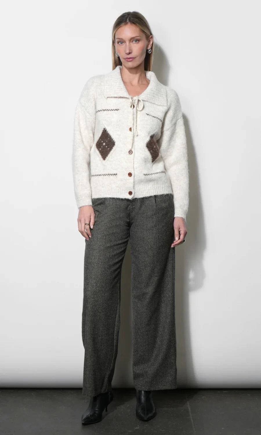Cream knit cardigan with button front, brown diamond patches, long sleeves, ribbed hem.