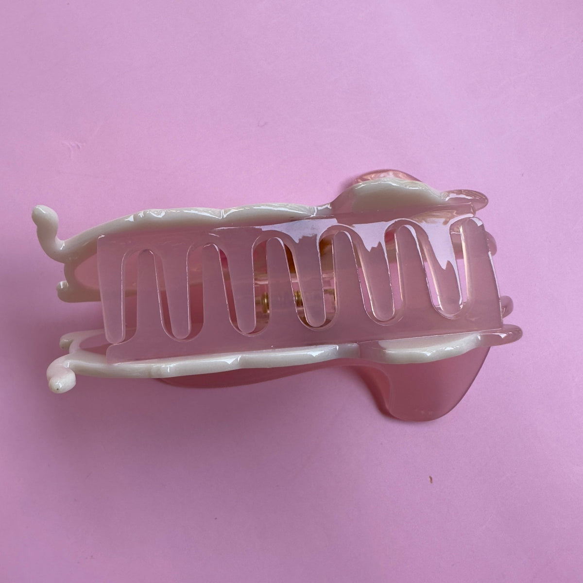 Pink translucent hair claw with curved teeth, side profile