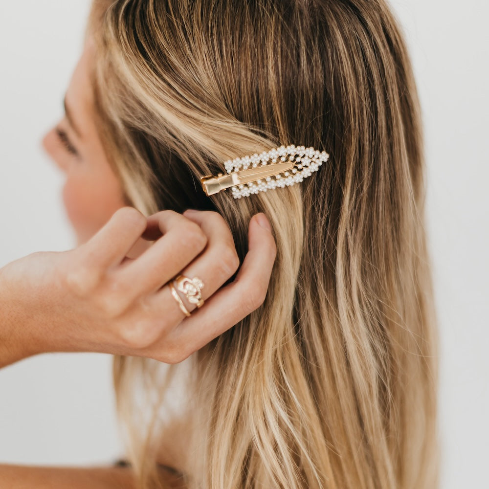 Pearl-and-diamond hair barrette clip with white stones, close-up on blonde hair