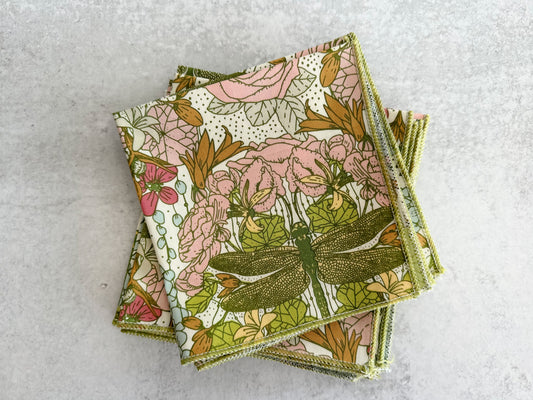 Set of four floral dragonfly cloth napkins, stacked with green border edges
