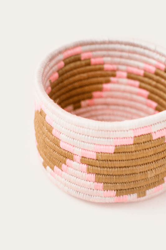 Close-up of pink, white, and brown woven trinket basket with striped pattern