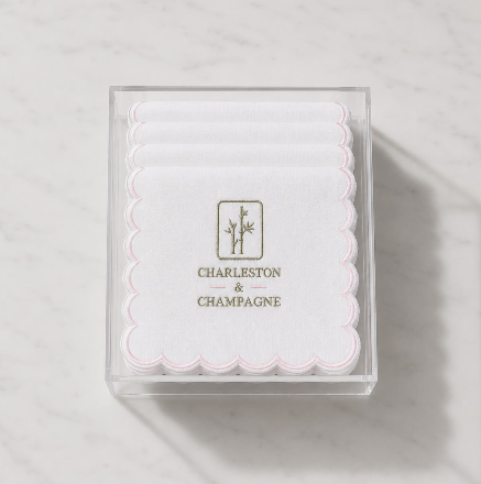 Embroidered cocktail napkin in clear box with Charleston & Champagne text and pink scallops