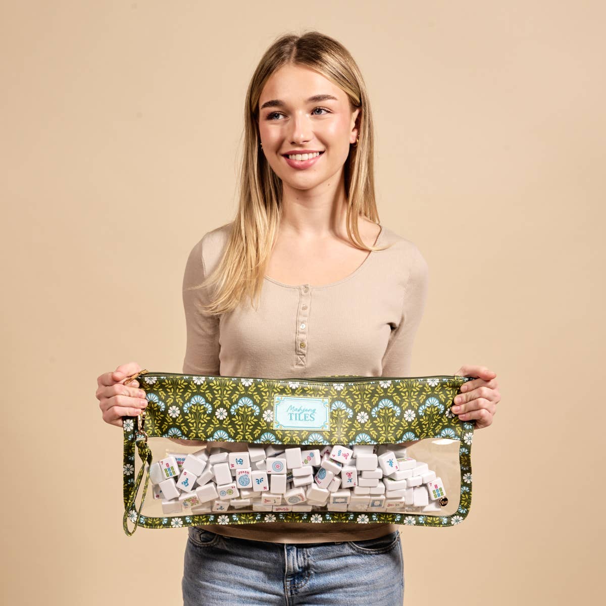 Forest green floral tile pouch held by model; visible zipper opening and tiles
