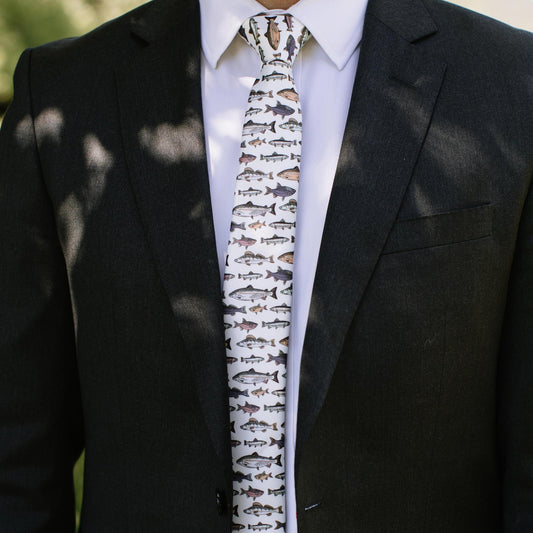 Men's fish-pattern necktie on black suit jacket, white base with small fish motifs