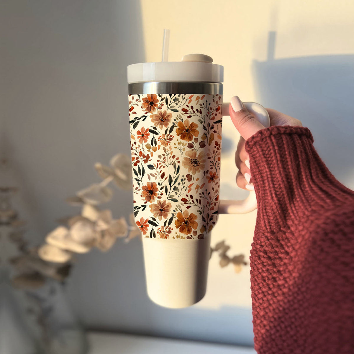 Autumn floral tumbler with straw and lid held by person in red sweater
