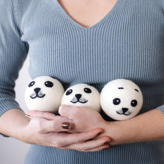 Three round panda plush toys held in hands, white felt faces with black eyes