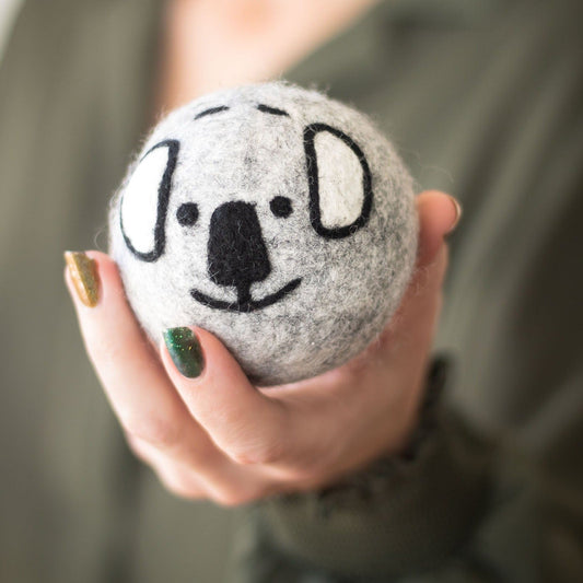 Gray koala plush ball with stitched smile and ears, held in someone’s hand