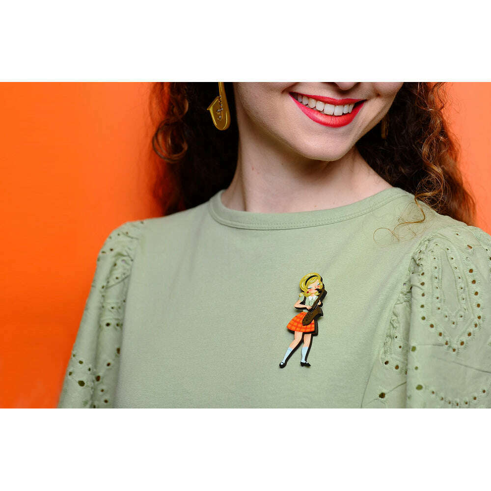 Saxophone girl brooch on light green blouse, orange plaid skirt, yellow hair, gold sax.