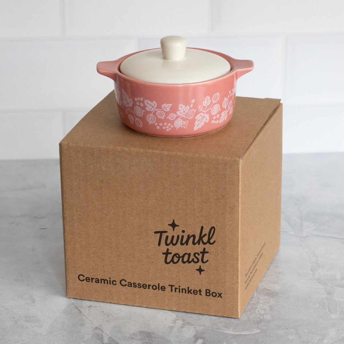Pink ceramic casserole trinket box with white lid on brown gift box packaging