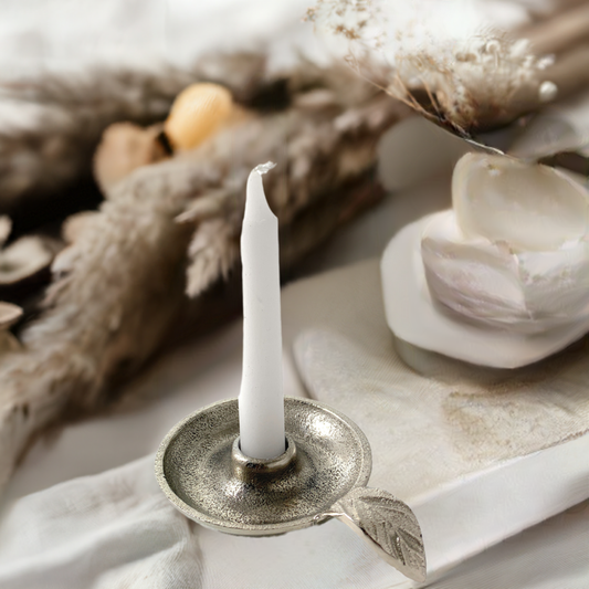 Silver taper candlestick holder with circular base and leaf handle, holds a white candle