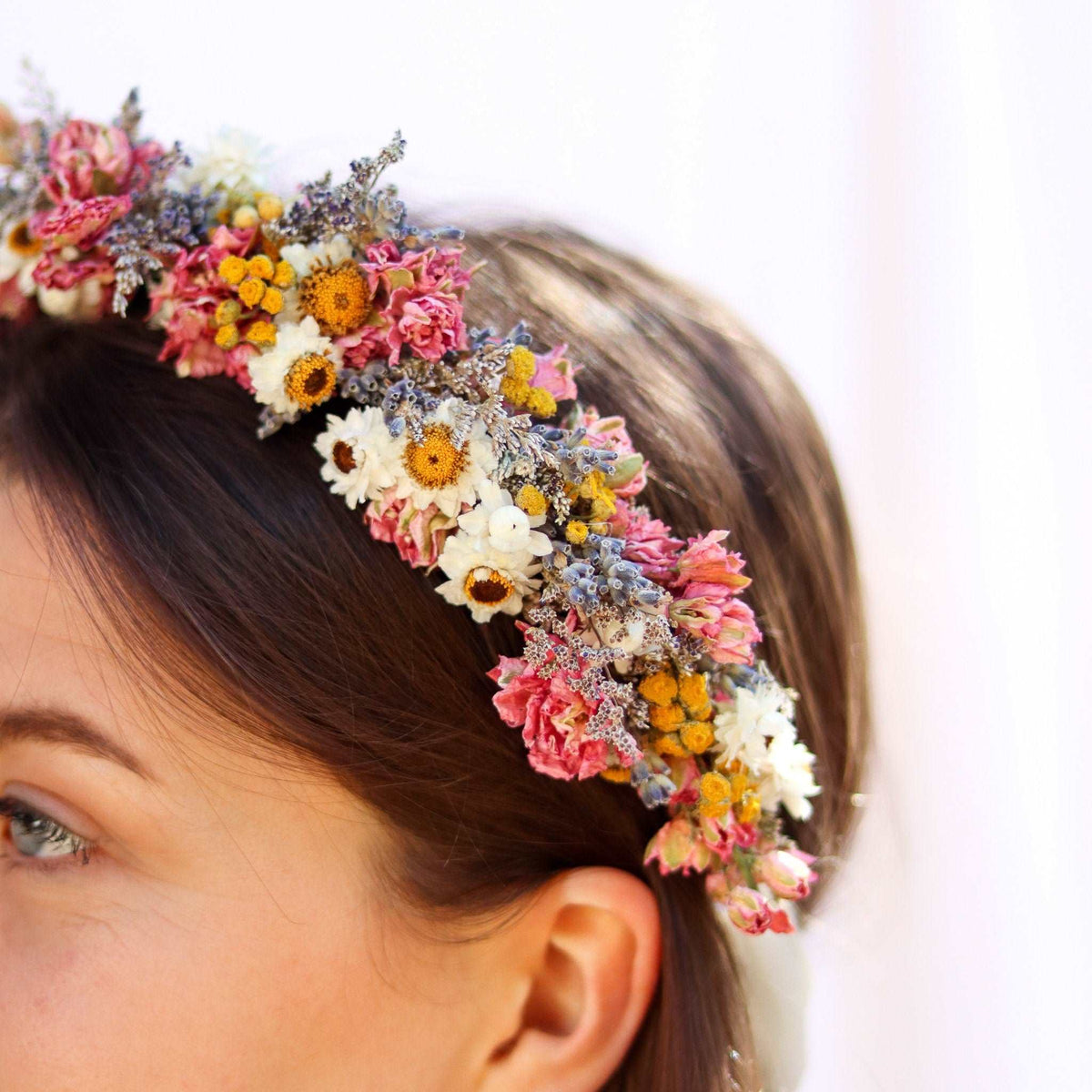 Close-up dried flower head wreath with pink and yellow blossoms on hair