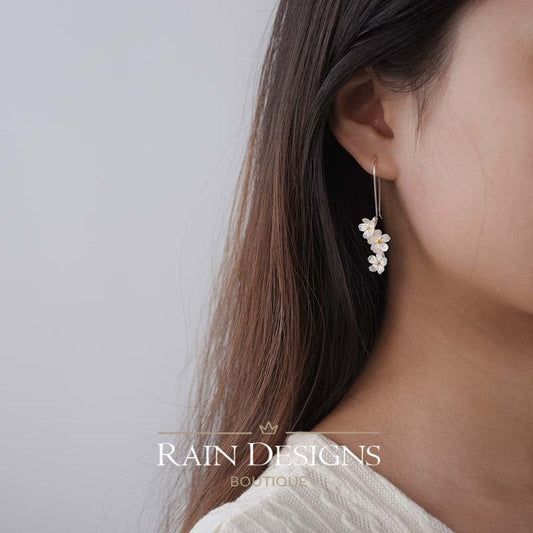 Silver floral hook earrings on ear, layered flower cluster drop