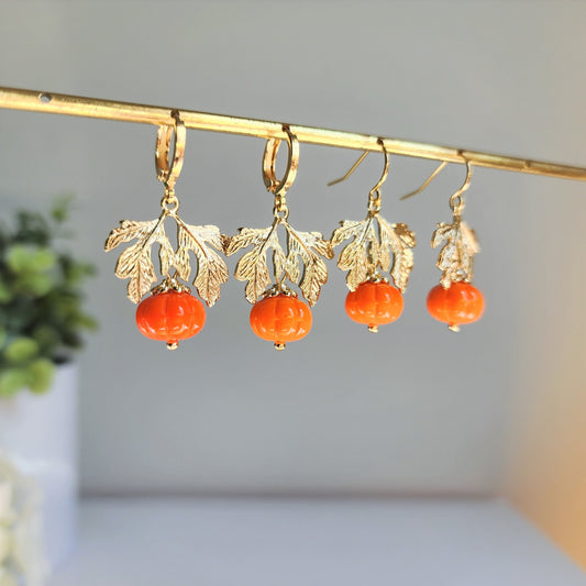 Gold-tone dangling earrings with orange pumpkin beads and textured leaf caps