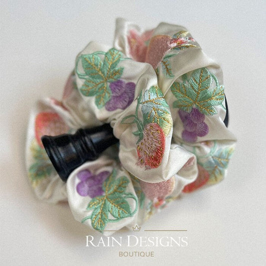 Ivory scrunchie with stitched strawberries, grapes, and leafy motifs in colorful thread.