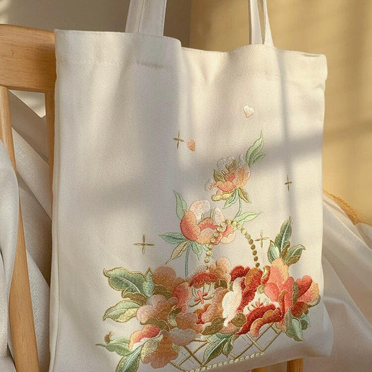 White embroidered tote bag with a colorful flower basket and small cross accents.