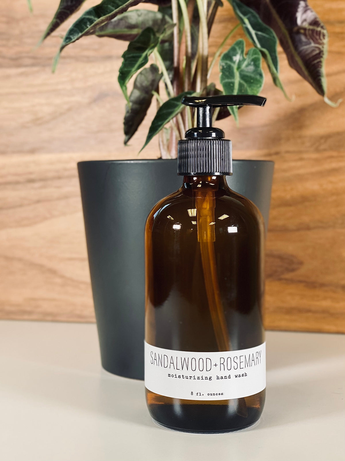 Amber hand wash bottle with black pump, sandalwood+rosemary label