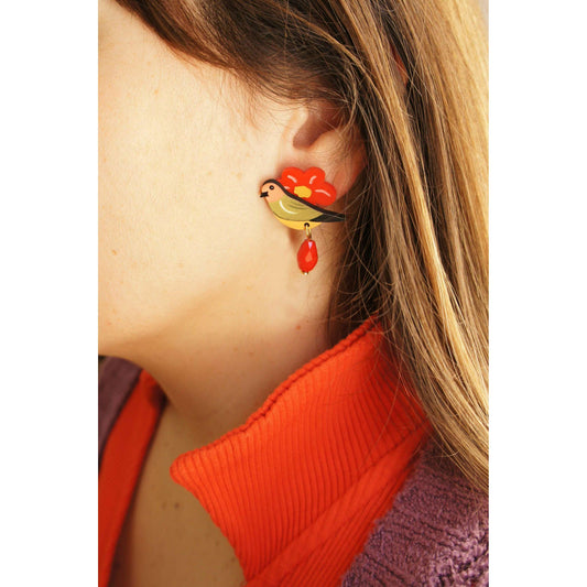 Bird and flower stud earrings with red teardrop dangle, shown on ear