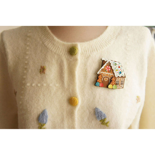 Gingerbread house brooch pin on cream sweater, colorful enamel house with red door